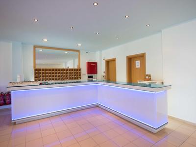 Modern, illuminated hotel reception with white counter and tiled floor