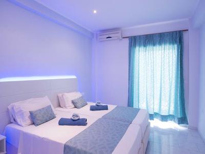 Bright hotel room with two single beds, blue accents, and plenty of natural light.