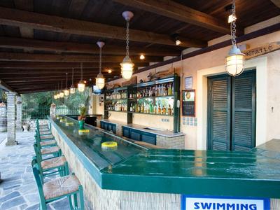 Long green bar with wooden roof and stools in an open terrace bar.