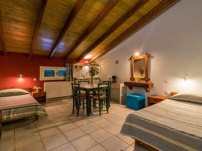 Gezellige zolderkamer met twee bedden en een kleine eethoek onder een schuine plafond.