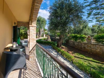 Balkon met stoelen en tafel met uitzicht op tuin met boom en stenen muur.