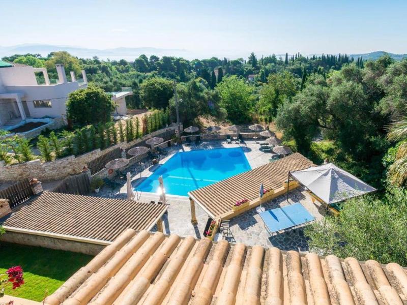 Uitzicht op een blauw zwembad in een tuin met huizen en bomen eromheen.