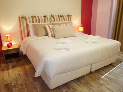 Světý hotelový pokoj s velkou manželskou postelí, dvěma nočními stolky a měkkým osvětlením.