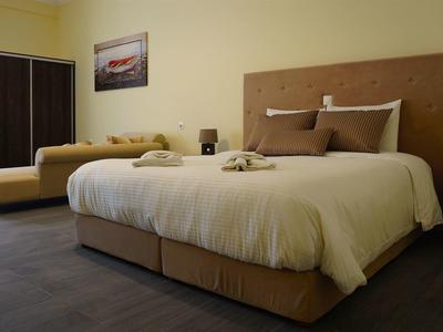 Pohodlný hotelový pokoj se dvěma postelemi, tmavou podlahou a obrazem na zdi.