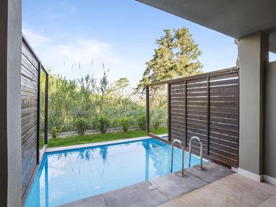 Soukromá oblast bazénu s dřevěnými clonami a výhledem na zahradu se stromy.