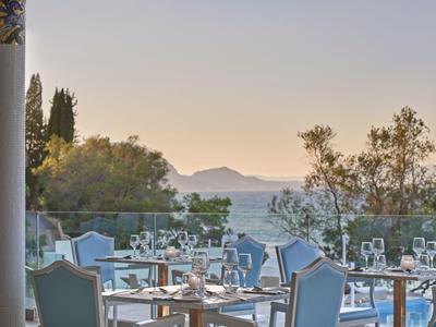 Terrazza del ristorante con tavoli apparecchiati e vista sul mare al tramonto.