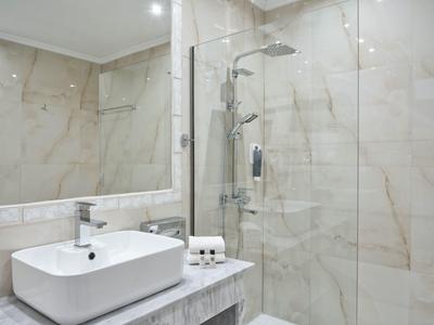 Modern bathroom with glass door shower and sink on marble countertop.