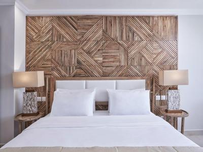 Camera d'hotel moderna con letto bianco, due lampade e parete decorativa in pannelli di legno sullo sfondo