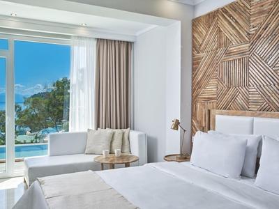 Modern hotel room with sea view, white furnishings, and wooden wall decor.