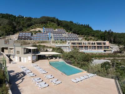 Hotelanlage auf einem Hügel mit mehreren Gebäuden und einem zentralen Außenpool, umgeben von Natur.