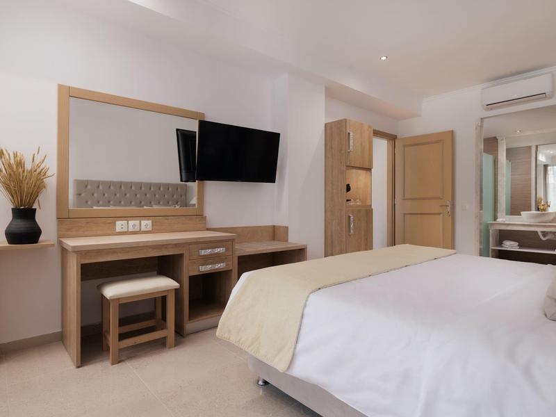 Helles Hotelzimmer mit Bett, Wandfernseher, Schreibtisch und Spiegel