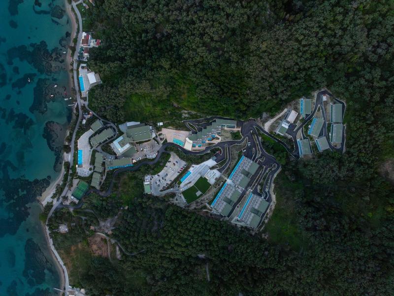 Luftaufnahme eines Resorts mit Pools, umgeben von dichtem Grün und Strand.