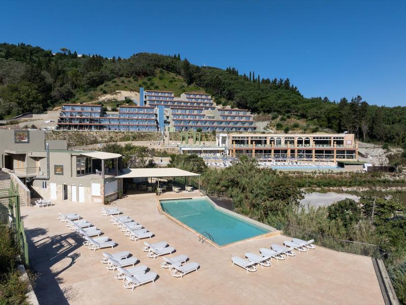 Hotelanlage auf einem Hügel mit mehreren Gebäuden und einem zentralen Außenpool, umgeben von Natur.
