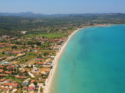 Vue aérienne d'une longue plage avec de l'eau turquoise et un paysage environnant.