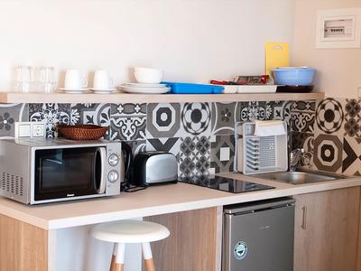 Coin cuisine compact avec micro-ondes, grille-pain, bouilloire et réfrigérateur dans une chambre d'hôtel.