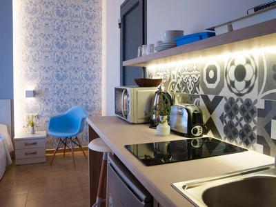 Cuisine d'hôtel moderne avec cuisinière, micro-ondes et chaise bleue à côté de la table.