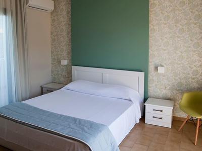 Chambre moderne avec lit double, mur accent vert et décor minimaliste.