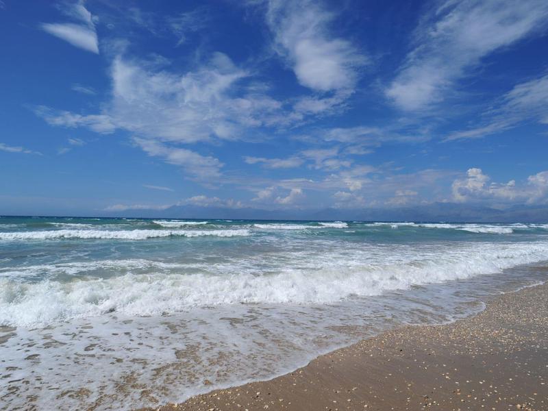 Plage côtière avec vagues et ciel bleu avec nuages