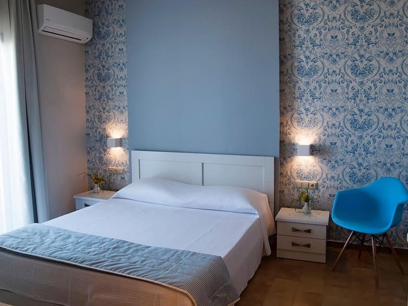 Chambre d'hôtel moderne avec lit double, mur bleu et siège avec chaise bleue.
