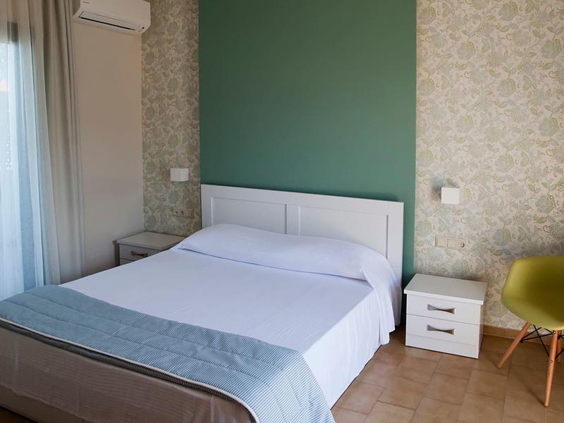 Chambre moderne avec lit double, mur accent vert et décor minimaliste.