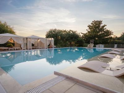 Pool area with sun loungers and covered lounge spaces at sunset