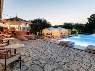 Hotelterrasse mit Sitzgelegenheiten und beleuchtetem Pool bei Sonnenuntergang.