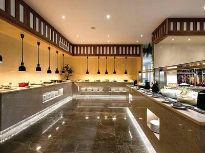 Moderne hotelkeuken met warme verlichting, lange werkbladen en glanzende stenen vloer.