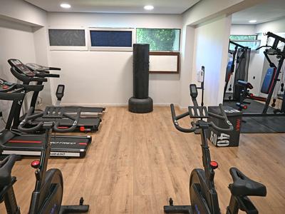 Moderne fitnessruimte met loopbanden, fietsen en een bokszak op houten vloer.
