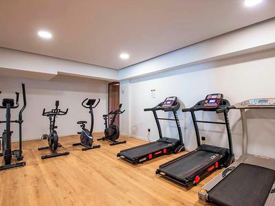 Moderne fitnessruimte met vier apparaten op houten vloer en wit geschilderde muren.
