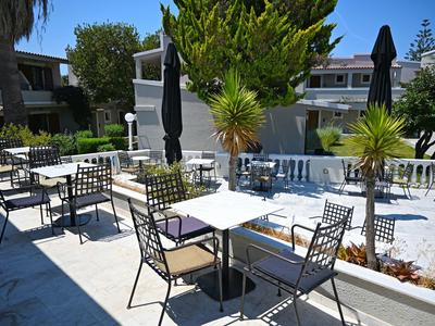 Buitengebied van een hotel met witte tafels en zwarte stoelen op een lichte terras.