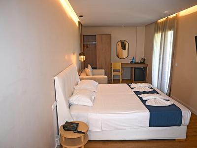 Modern hotelkamer met tweepersoonsbed, nachtkastje en aan de muur bevestigd tv-scherm naast raam met gordijnen.