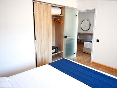 Modern hotelkamer met open kast en uitzicht op aangrenzende slaapkamer.
