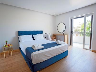 Modern hotelkamer met tweepersoonsbed, houten vloer en balkonzicht met groen.