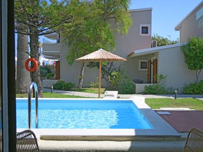 Modern hotelzwembad met parasol, ligstoelen en aangrenzend tuingebied.