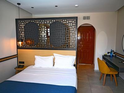 Modern hotelkamer met tweepersoonsbed, blauw bedsprei en houten stoel bij bureau.