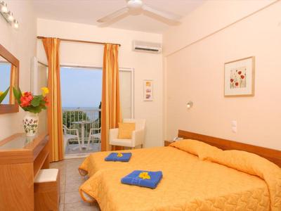 Příjemný hotelový pokoj s manželskou postelí, balkonem a teplými tóny.