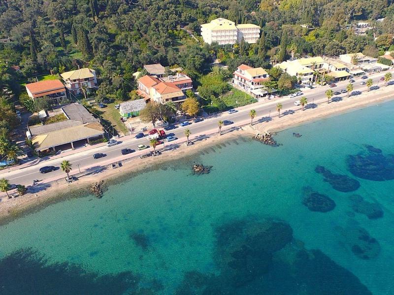 Vista aérea de una playa con agua turquesa clara y una carretera costera con edificios.