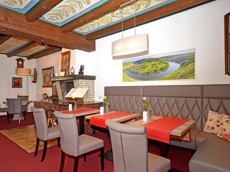 Salle à manger d'hôtel confortable avec fauteuils, cheminée et plafond décoratif.