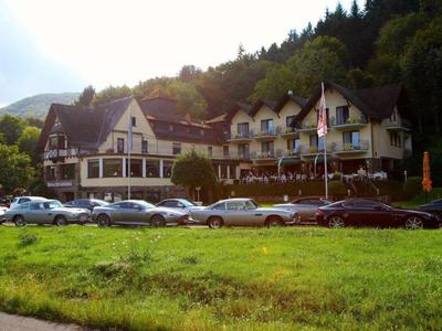 Großes traditionelles Hotel in einem bewaldeten Berggebiet mit vielen geparkten Autos davor.