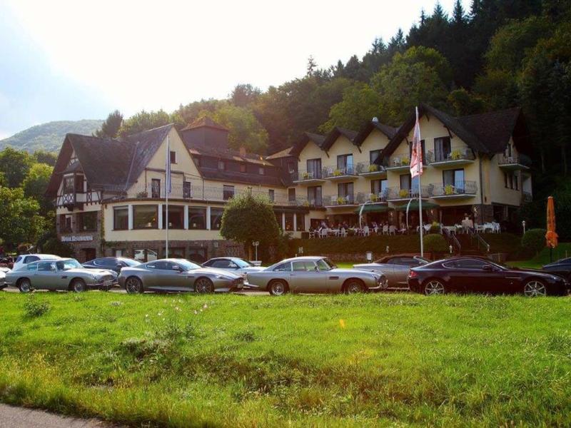 Großes traditionelles Hotel in einem bewaldeten Berggebiet mit vielen geparkten Autos davor.