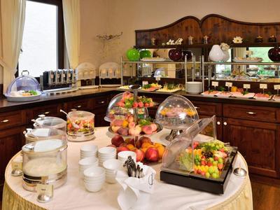 Buffet mit Obst, Eis und Getränken auf rundem Tisch vor antiken Holzschränken in hellem Raum.