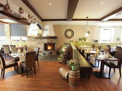 Gemütliches Restaurant mit Holzboden, Kamin und elegant gedeckten Tischen.