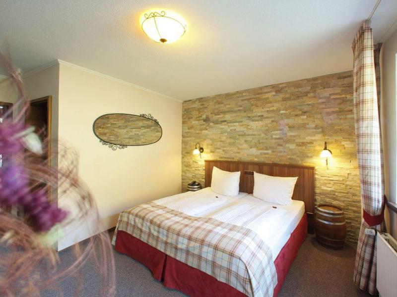 Gemütliches Schlafzimmer mit großem Bett, Steinwand, warmem Licht und Vorhängen am Fenster.