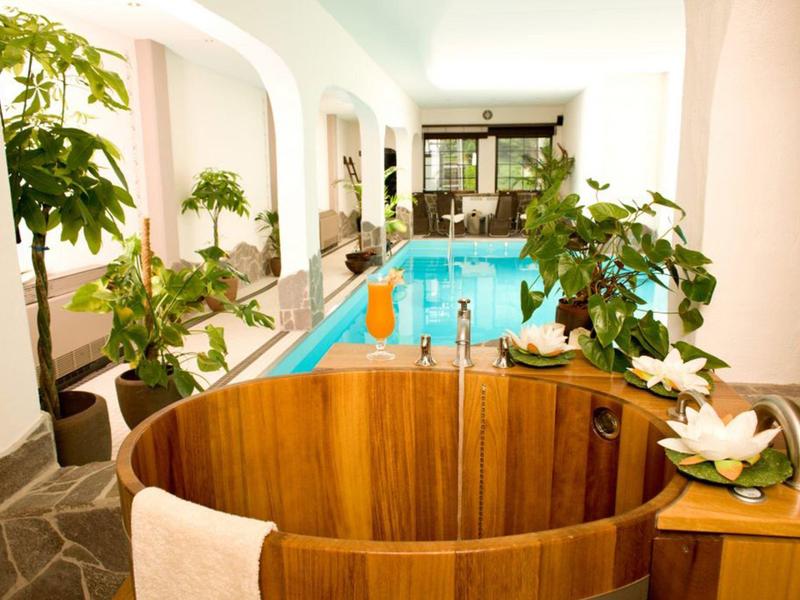 Helles Zimmer mit rundem Holzbad, Pool und grünen Pflanzen für entspannte Atmosphäre.