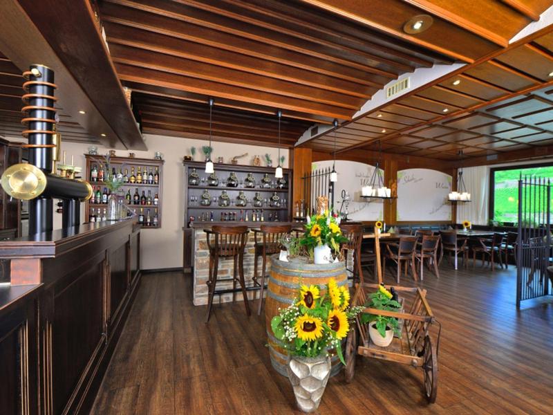 Gemütliche Bar mit Holzbalken, Theke, hohen Stühlen und Sonnenblumen-Dekor im Glas.