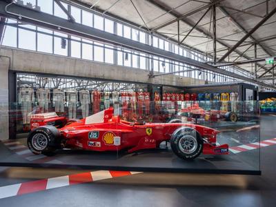 Roter Formel-1-Rennwagen in einer modernen Ausstellungshalle.