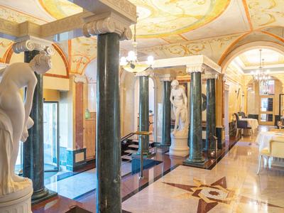 Prächtiger Hotellobby mit Marmorsäulen, klassischen Statuen und elegantem Mobiliar.