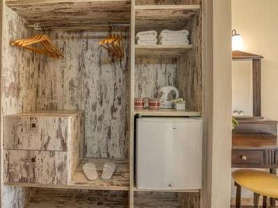 Armoire ouverte en bois avec chaussures, serviettes et mini-réfrigérateur.