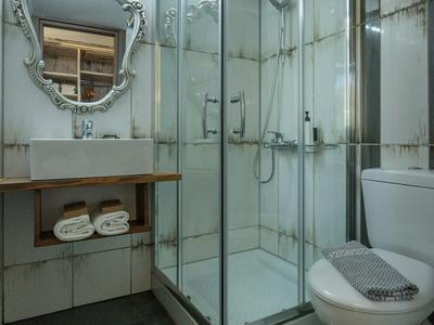 Salle de bain moderne avec douche en verre, toilettes et miroir décoratif dans une chambre d'hôtel.
