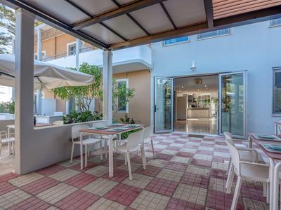 Espace extérieur couvert avec tables et chaises devant l'entrée d'un hôtel.